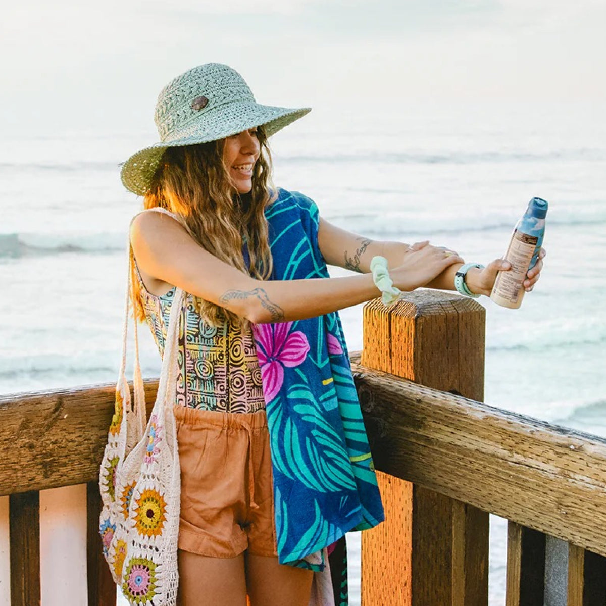 Woman applying sunscreen at the beach with ocean in the background