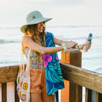 Woman applying sunscreen at the beach with ocean in the background