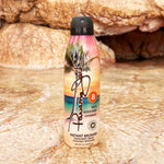 Sunscreen spray bottle with tropical design on a rocky surface