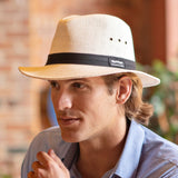 Man wearing a straw Panama Jack hat with a black band, outdoors.