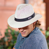 Person wearing a white Panama Jack hat with a black band outdoors