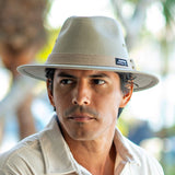 Man wearing a beige Panama Jack hat with a blurred natural background