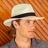 Man wearing a Panama Jack straw hat with a black band against a wooden background