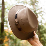 Panama Jack hat held by a hand with a forest background