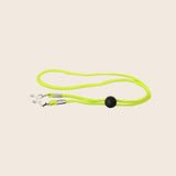 Neon green Panama jack sunglasses cord with a clip on a beige background