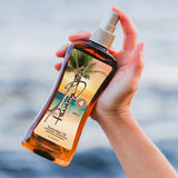 Hand holding a bottle of Panama Jack Sunscreen Oil with a scenic label against a blurred background