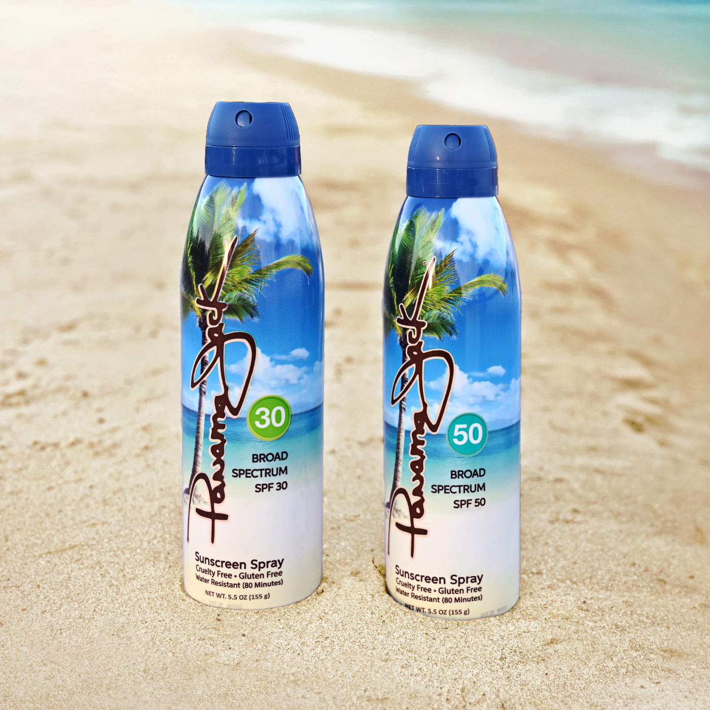 Panama Jack sunscreen spray bottles on a sandy beach with a tropical background.
