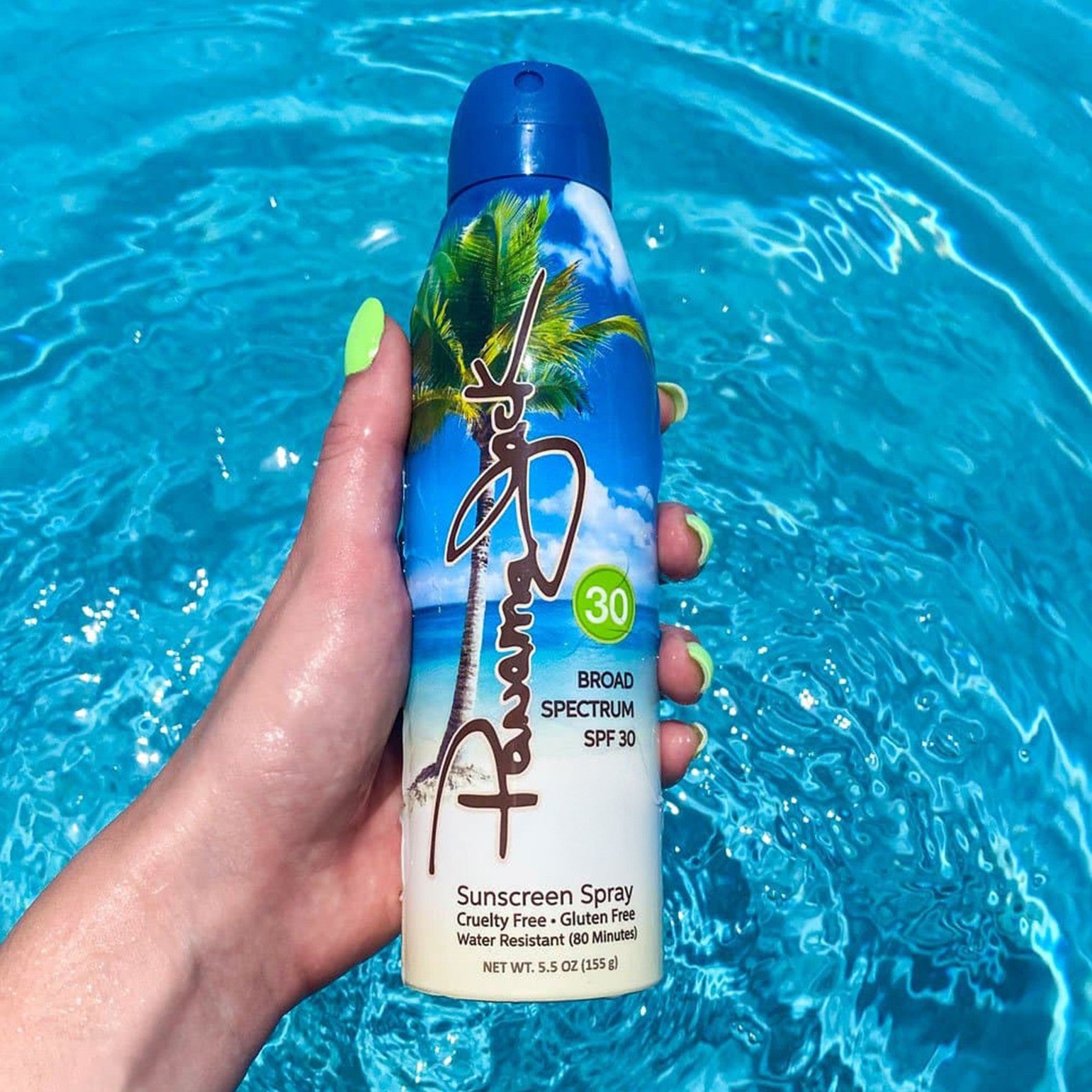 Hand holding a Panama Jack sunscreen SPF 30 spray bottle with a blue background