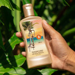Hand holding a Panama Jack SPF 8 sunscreen lotion bottle with a tropical design against a green leafy background