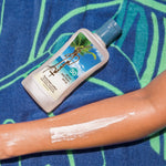 Panama Jack Sunscreen bottle with application on arm against a blue and green patterned background