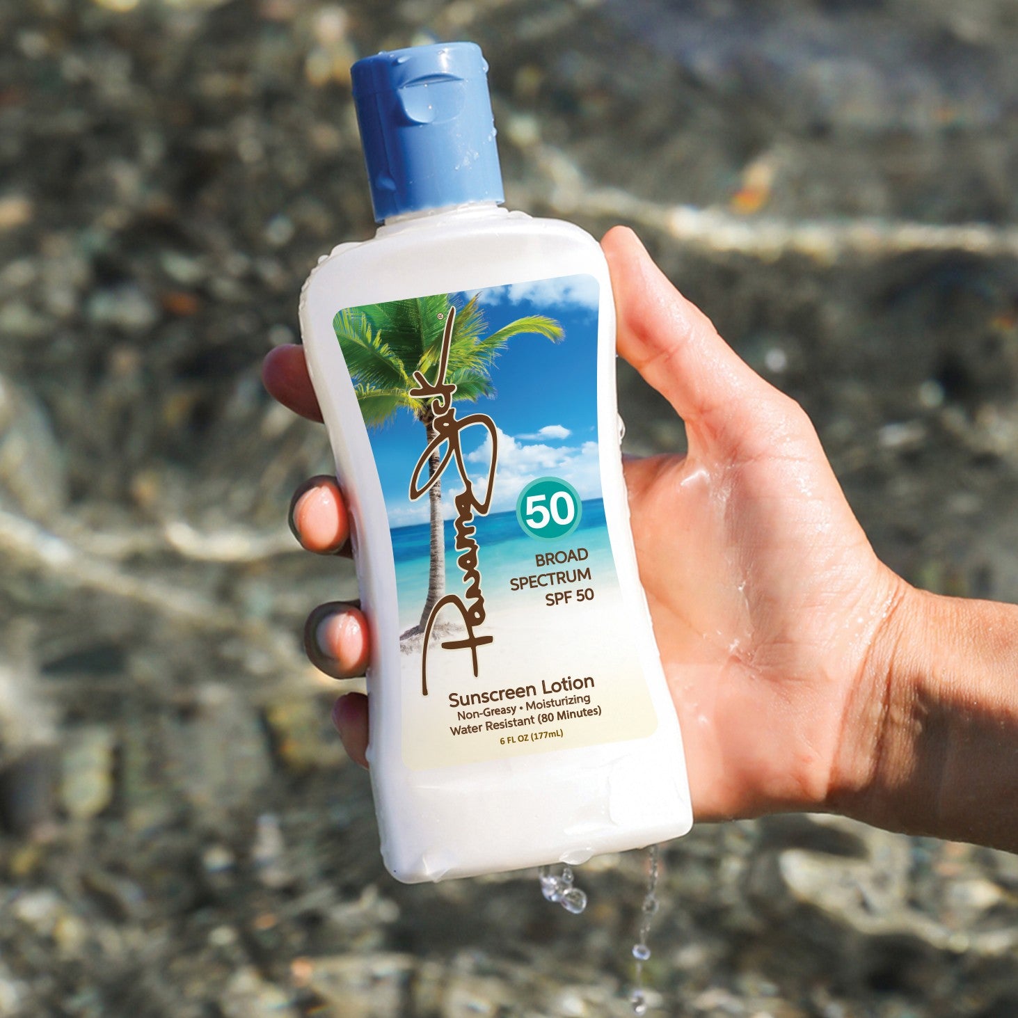 Hand holding a sunscreen lotion bottle with a beach background