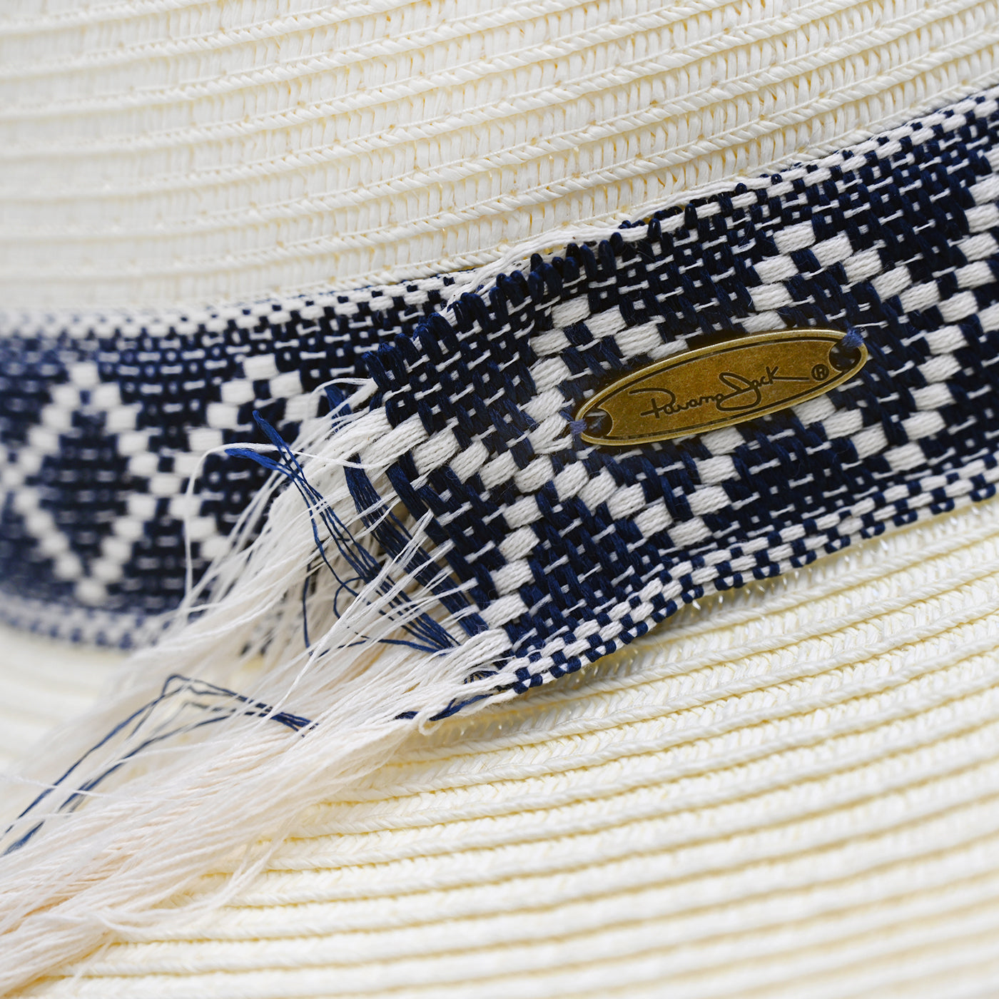Close-up of a Panama Jack straw hat with a blue and white patterned band and a brand logo.