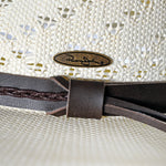 Close-up of a woven Panama Jack hat with a leather band and brand logo.