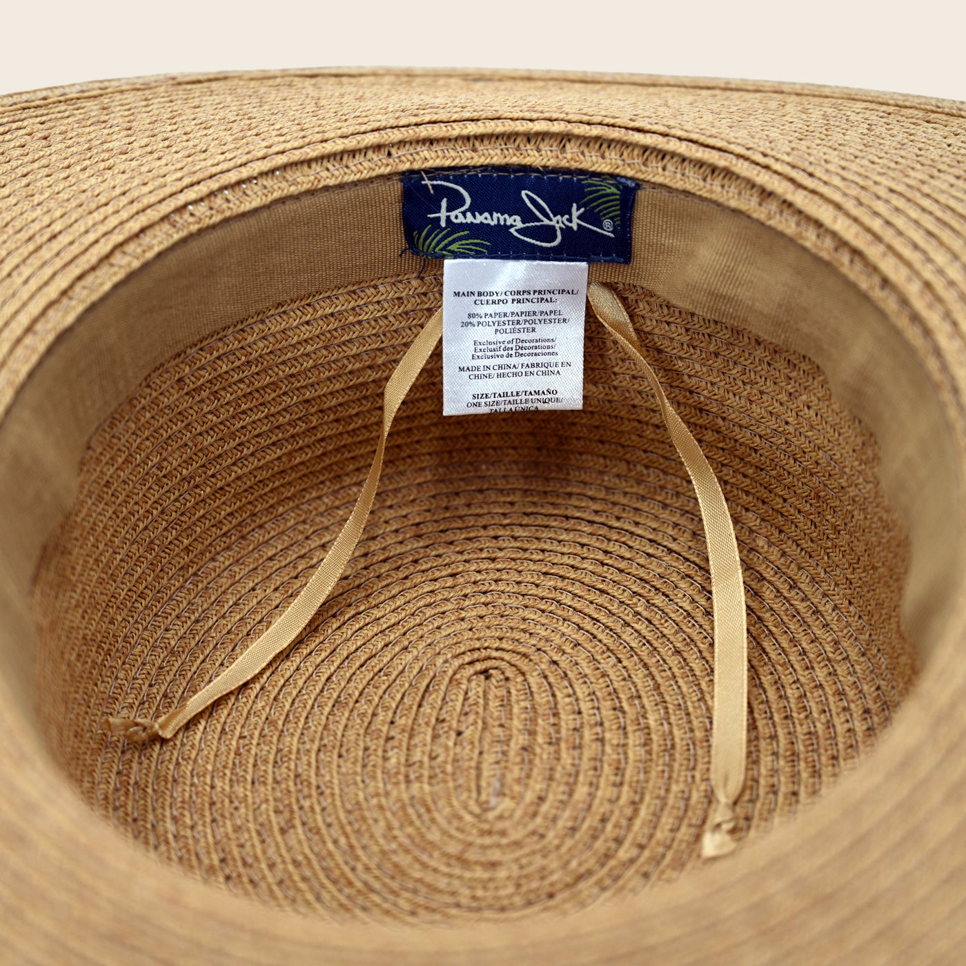 Close-up of a straw Panama Jack hat with a brand label on a beige background