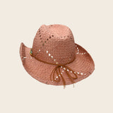Pink straw Panama Jack hat with a brown ribbon on a beige background