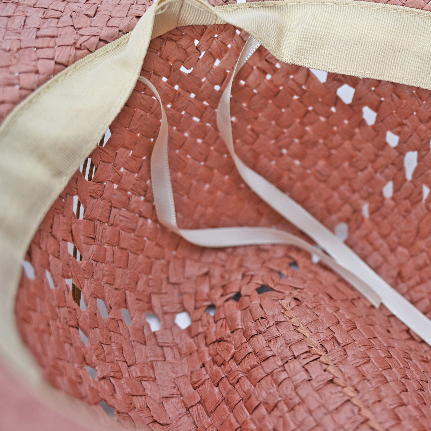 Close-up of a pink straw Panama Jack hat with a beige ribbon