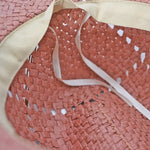 Close-up of a pink straw Panama Jack hat with a beige ribbon