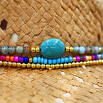 Panama Jack Colorful beaded bracelet with a large turquoise stone on a straw surface