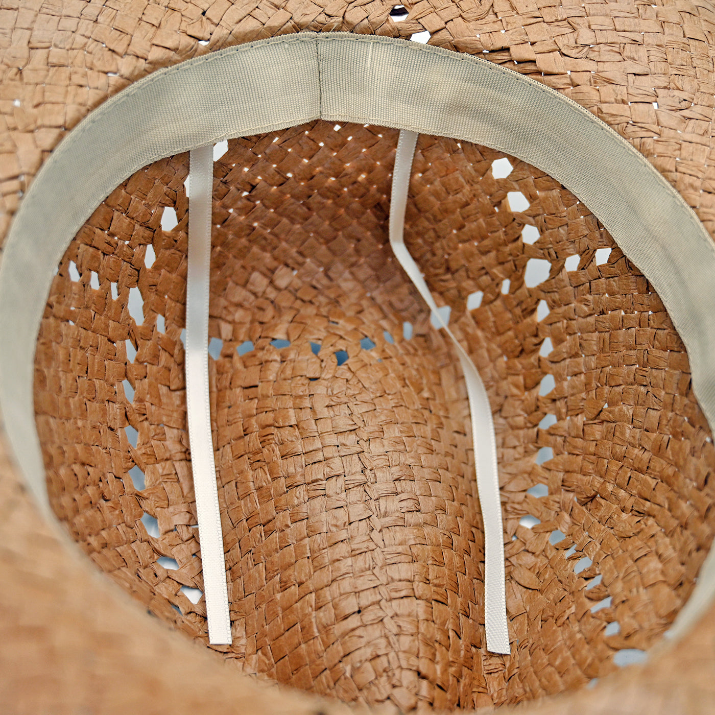 Close-up of a straw Panama Jack hat with a woven pattern and visible stitching.