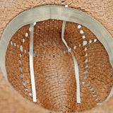 Close-up of a straw Panama Jack hat with a woven pattern and visible stitching.